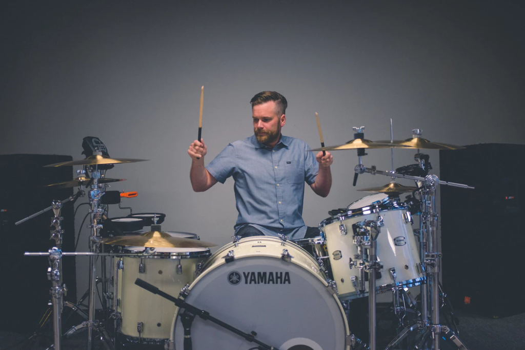 Man playing drums and hitting cymbals with drum sticks