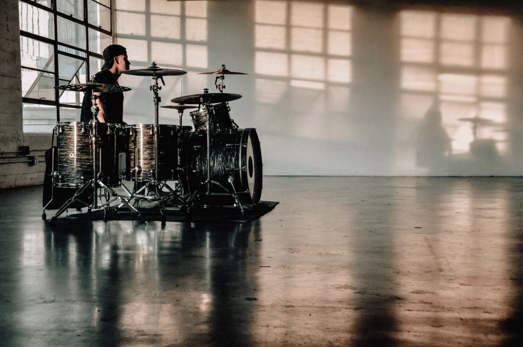 Drummer sitting at rock drum kit in big room