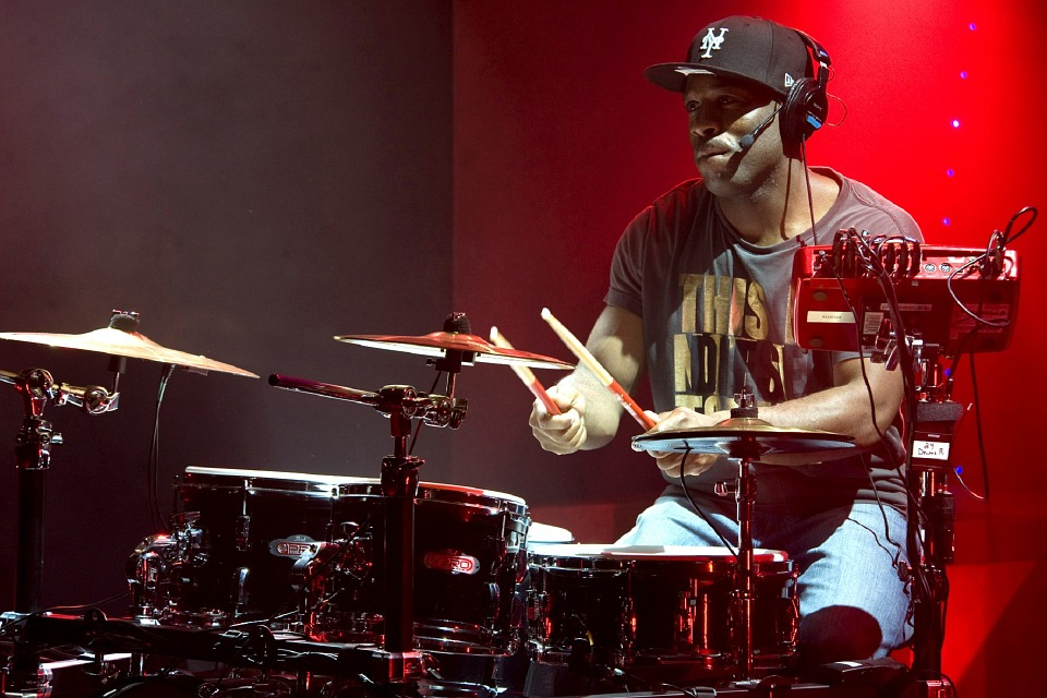 Drummer sitting on drum throne playing drums