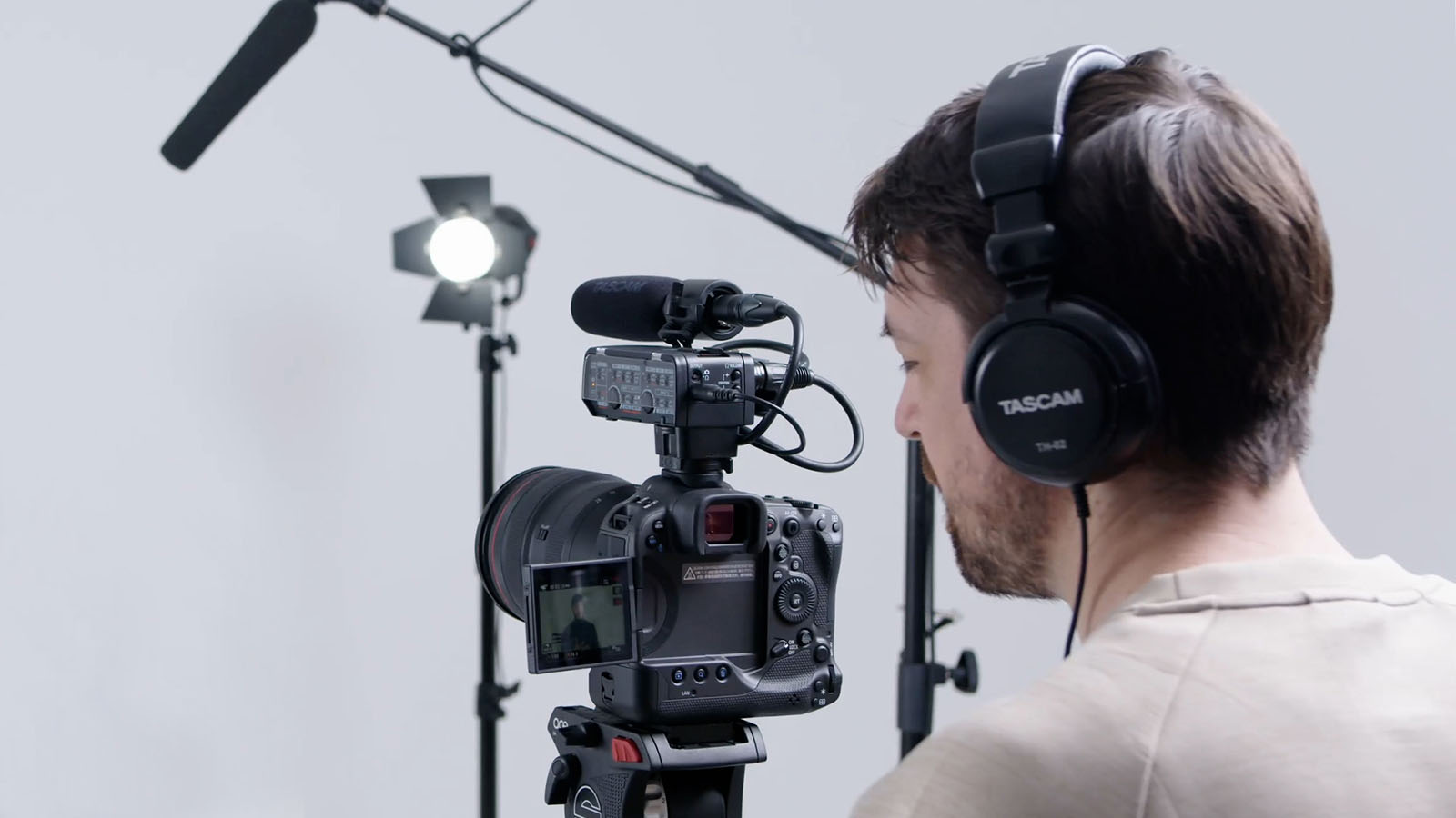 man using TASCAM CA-XLR2D DSLR camera microphone and sound recorder