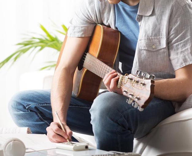 image of man with guitar writing a song